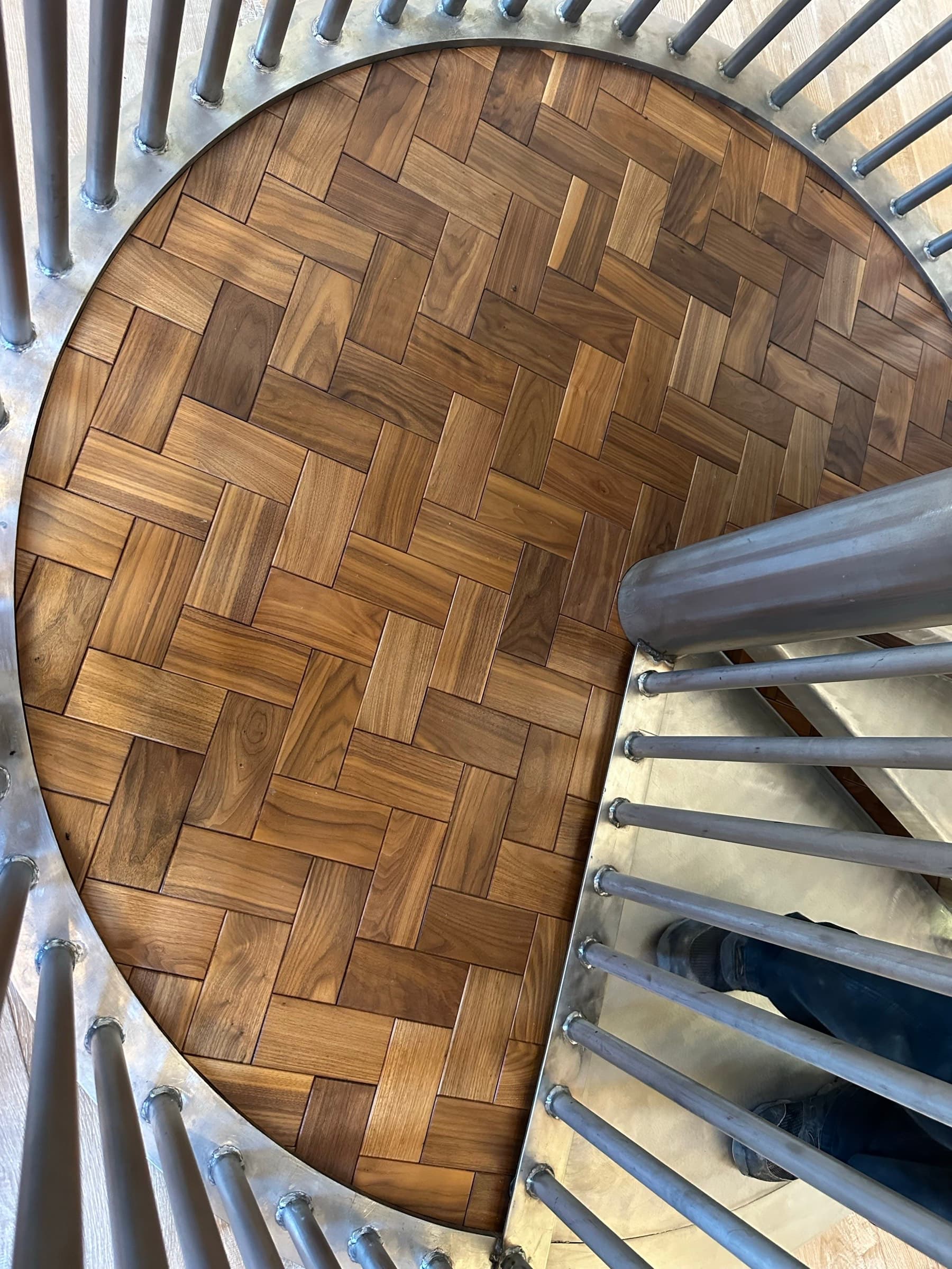 Walnut herringbone parquet floor beneath a spiral staircase