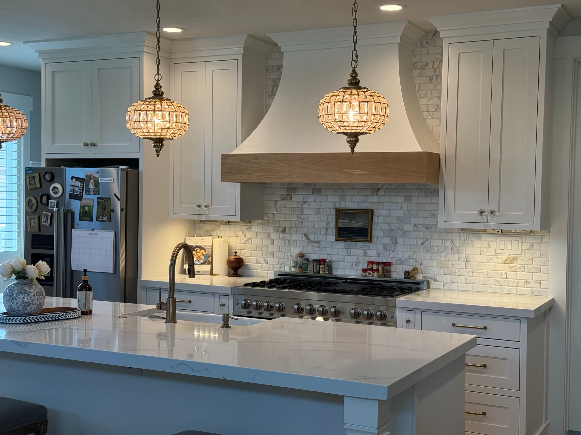 White inset kitchen with a custom wood range hood by Peterson Cabinets & Trim
